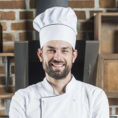 Chef with white hat and uniform smiling
